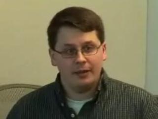 a man wearing glasses and smiling at the camera