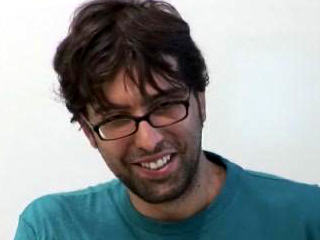 a man wearing glasses and smiling at the camera