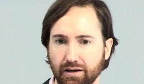a man wearing a suit and tie smiling at the camera