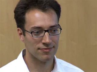 a man wearing glasses and smiling at the camera