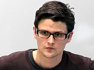 a man in glasses looking at the camera