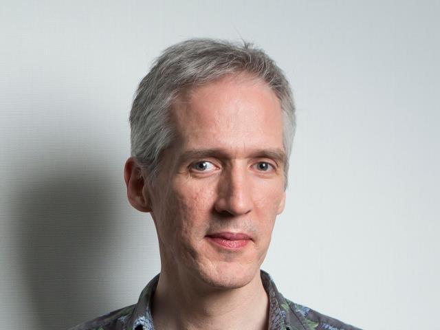 a man wearing glasses and smiling at the camera