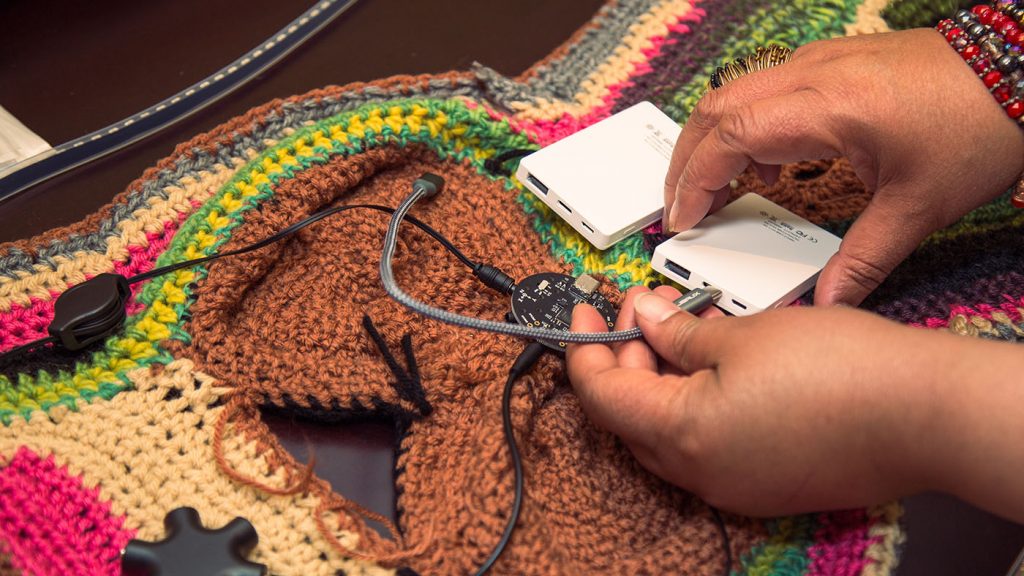 Project Brookdale: photo of a woman's hands plugging in the circuits woven into garment
