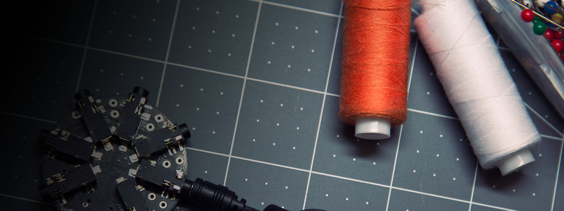 Project Brookdale: photo of a round circuit, spools of orange and white thread, and a box of colorful beads