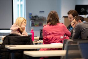 a group of people sitting at a table using a laptop