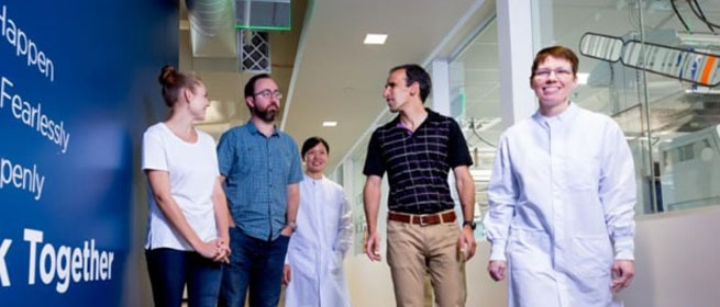 Group of men and women walking down a lab hallway
