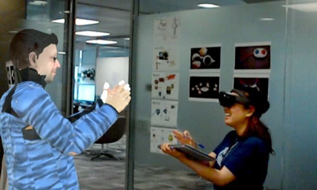 Senior Researcher Sean Rintel, using VROOM, interacts with Research Assistant Priscilla Wong, who is wearing a HoloLens. Sean’s photorealistic avatar is clapping along with Priscilla.