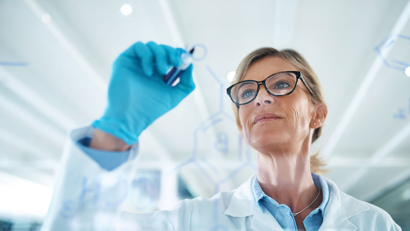 female scientist writing equations on a clear panel