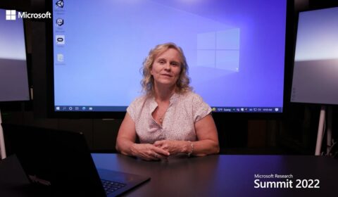 a person sitting at a table in front of a computer screen