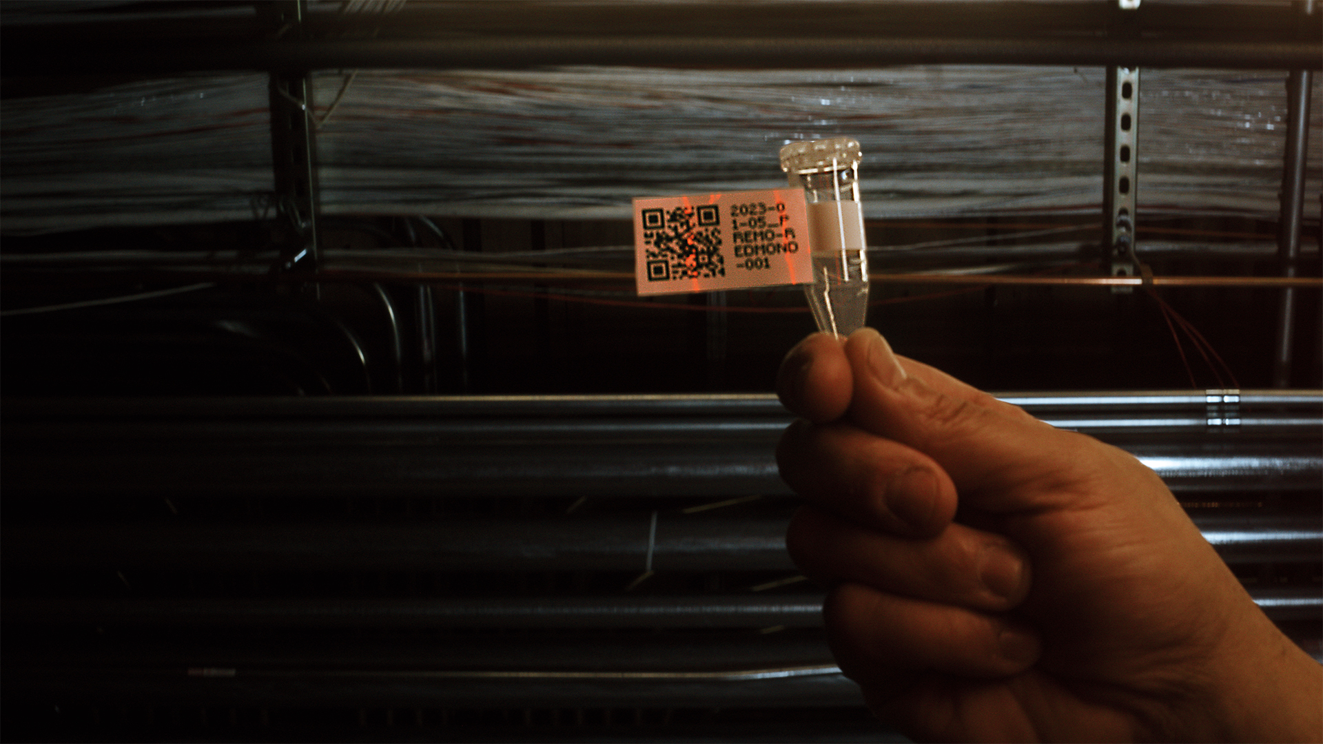 close up photo of a hand holding a test tube with a QR code
