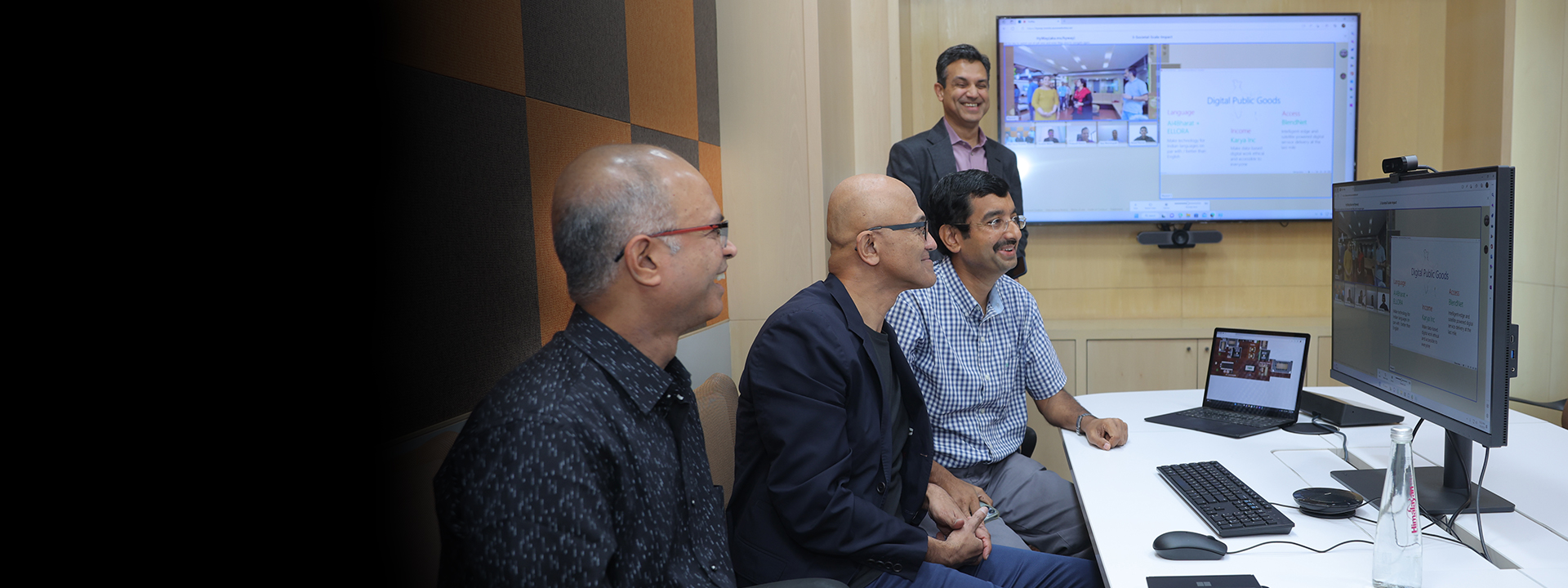a group of people sitting at a desk looking at a laptop