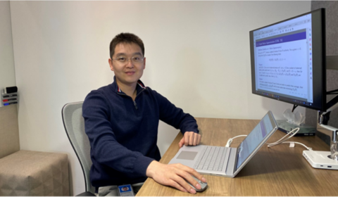 a person sitting at a desk in front of a laptop computer