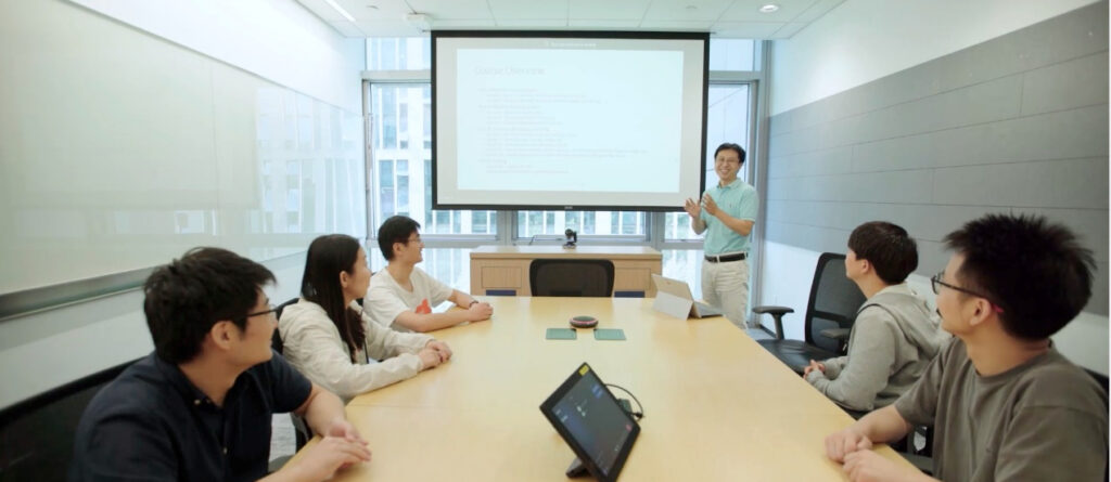 a group of people sitting at a table using a laptop