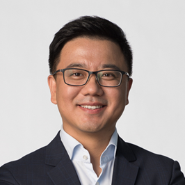 a man wearing a suit and tie smiling at the camera