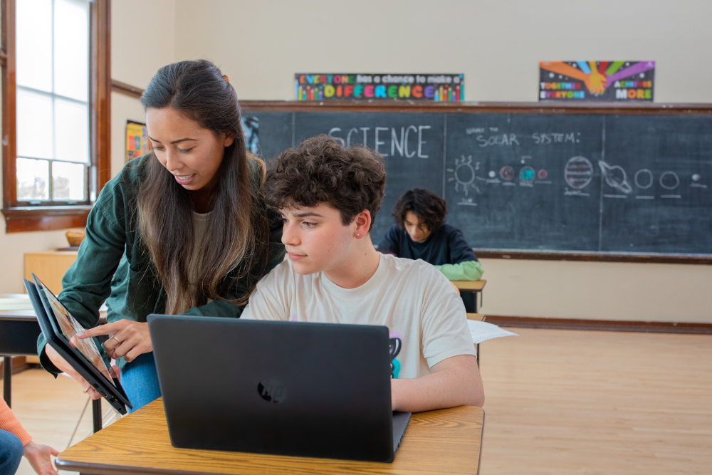 a group of people sitting at a table using a laptop computer