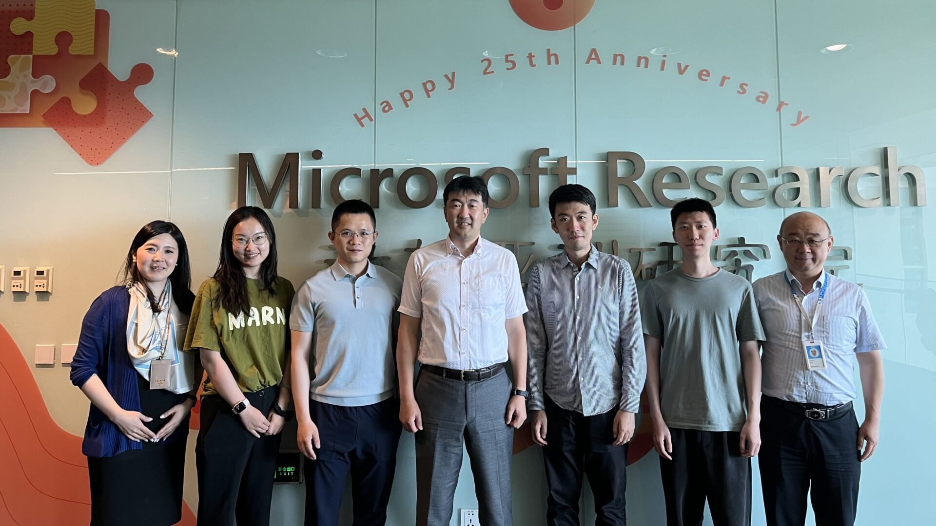 Group photo in front of Microsoft Research Asia - Happy 25th Anniversary wall
