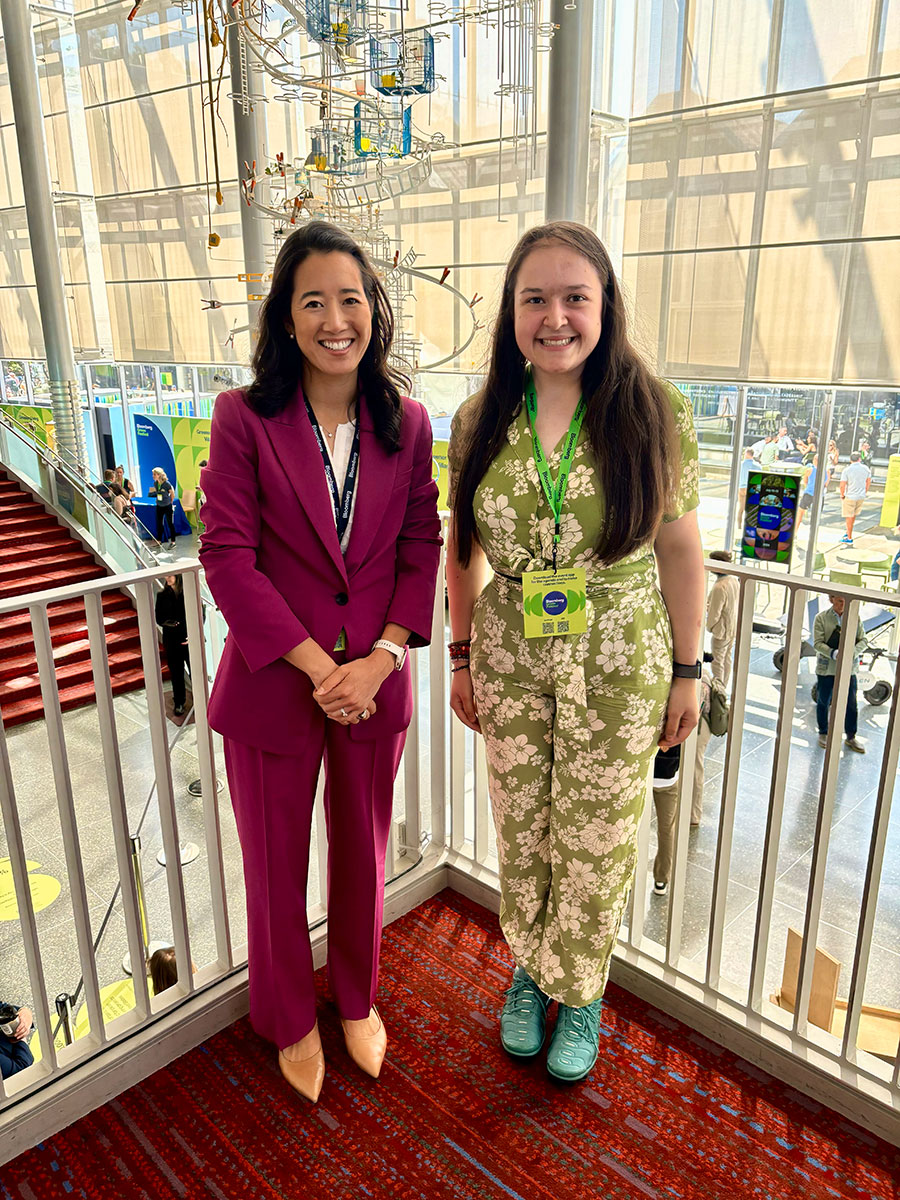 Angela Busheska and Melanie Nakagawa standing in front of a fence