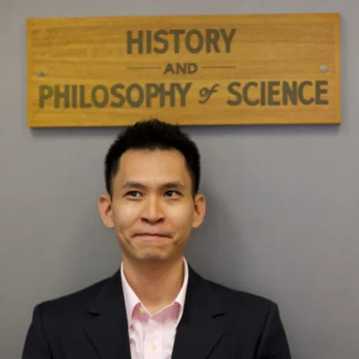 a person wearing a suit and tie smiling at the camera