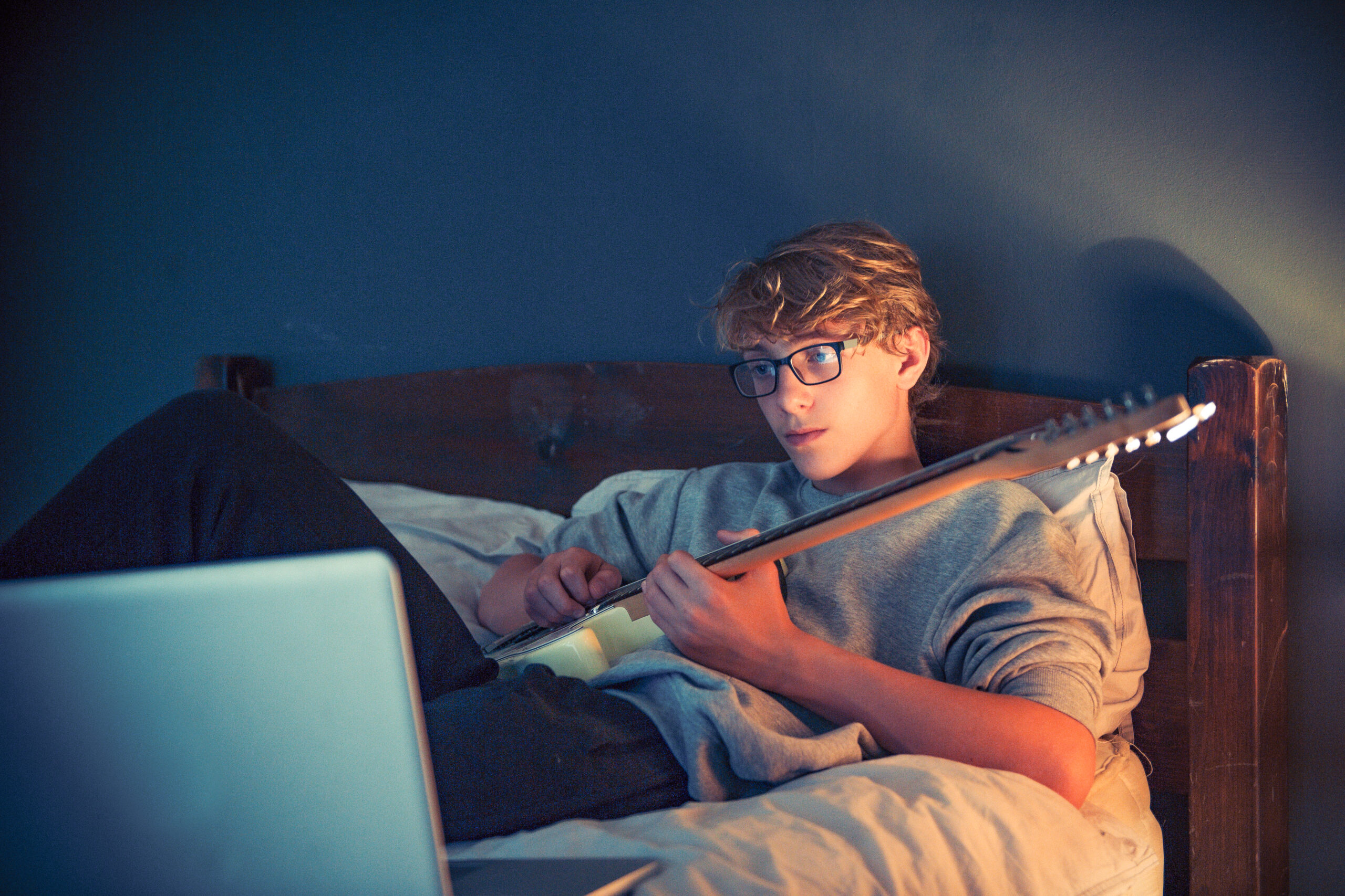 Teenager playing guitar while using AI to learn