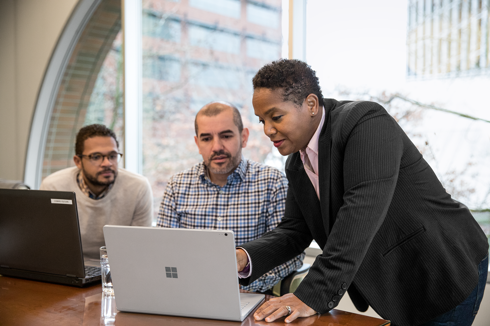 Image of three coworkers working at a desk in an office.