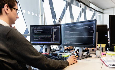 A tech worker using a dual screen PC workstation.