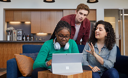 Image of students hovered over a computer.