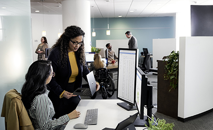 Two women collaborate over a desk at work.