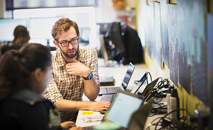 Image of several coworkers collaborating over a computer in an office.