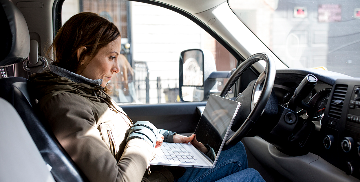 Image of a worker in her car with a laptop.
