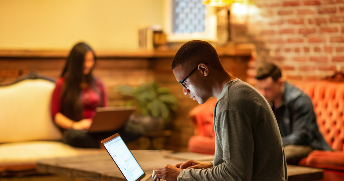 Male developer working remotely from a caf&eacute;.
