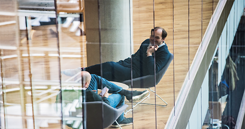 Image of two executives in the tech industry chat while seated in common area of UK office.