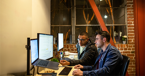 An image oft two male developers working and collaborating in an casual enterprise office.