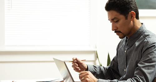 An image of a man working remotely on a Dell Latitude 7410 from his diningroom table.