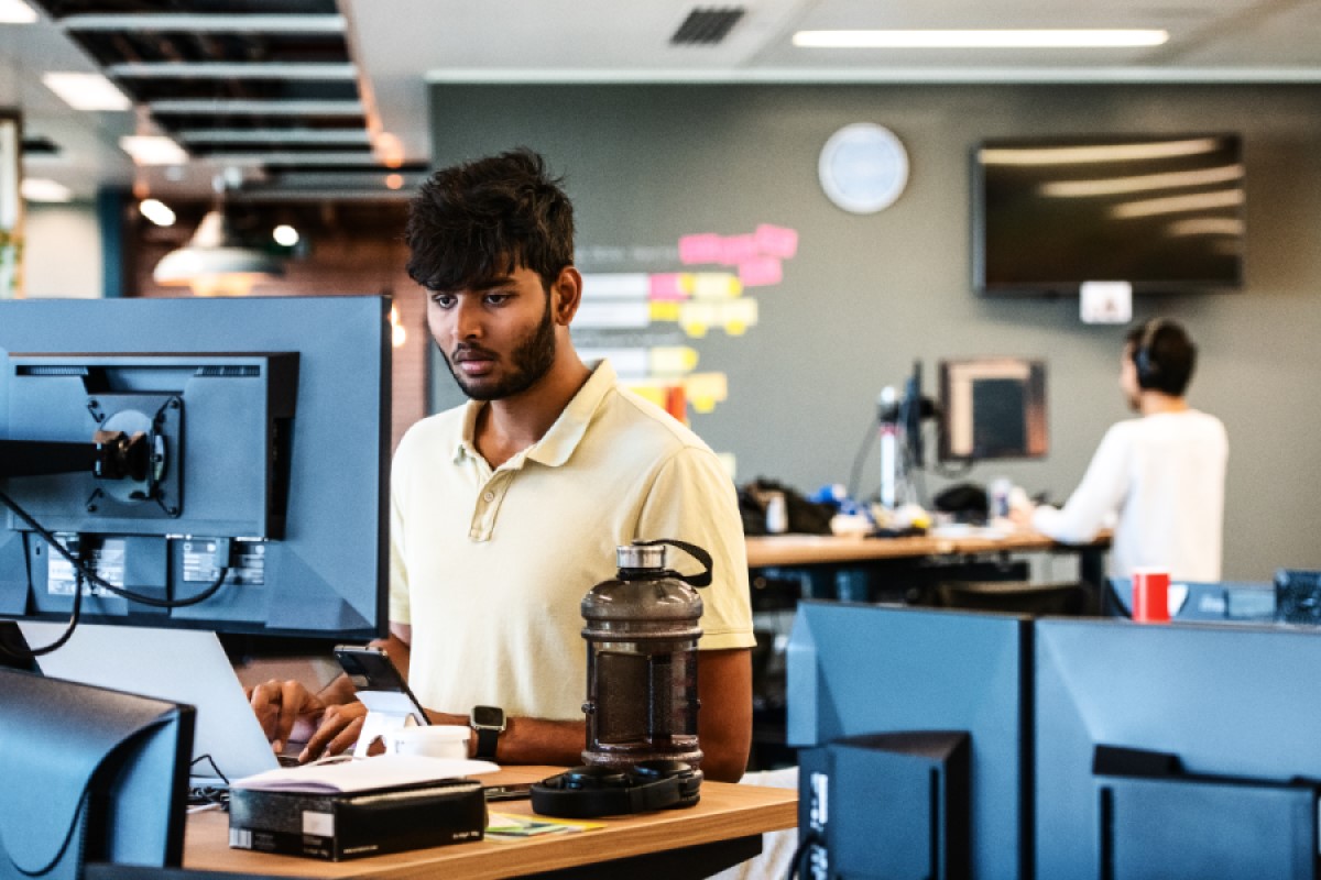 An employee in the tech industry works at a standing desk in UK office.