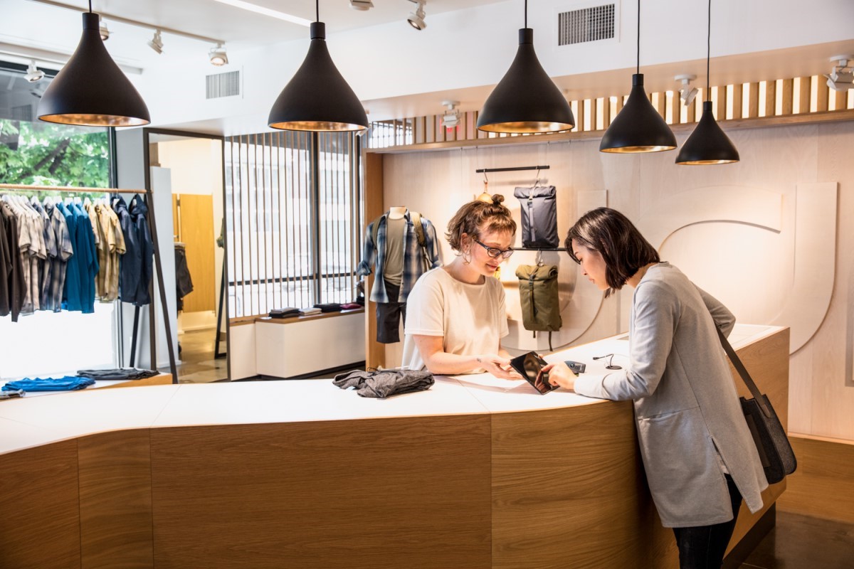 Woman pays for clothing at register.