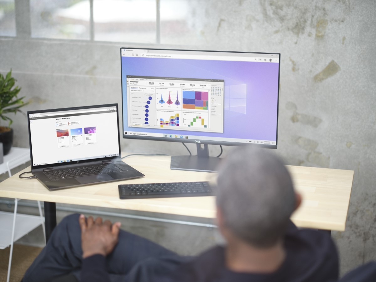 Man sitting at a desk viewing Power BI and Welcome Screen within Windows 365.