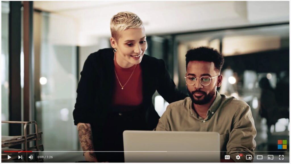 Two professionals work on a single laptop together, collaborating on a project. 