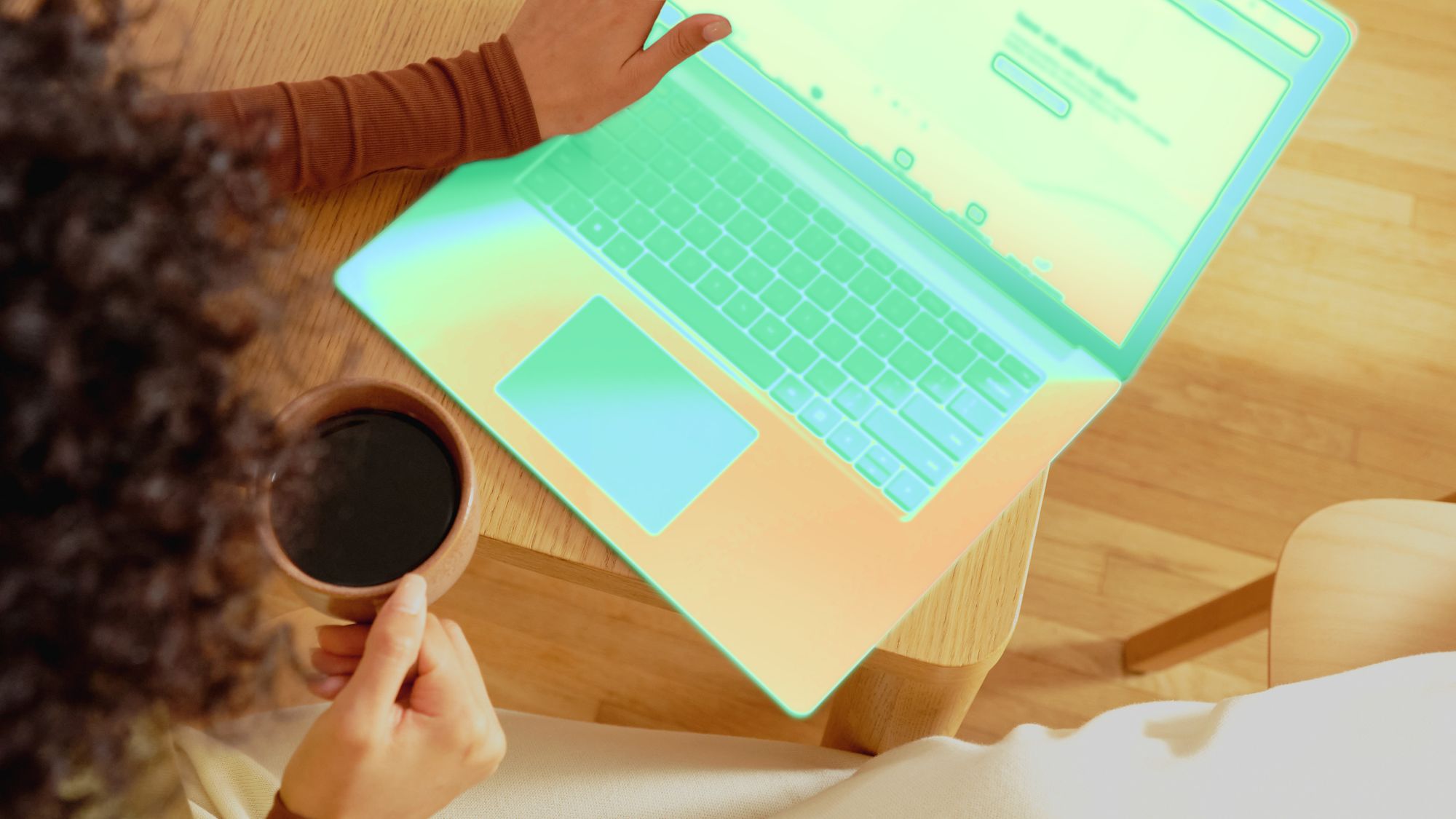 A person holding a cup of coffee and a laptop