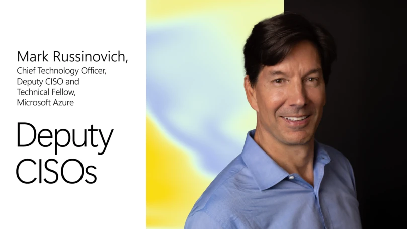 A man in a blue shirt with yellow and blue background and black text.