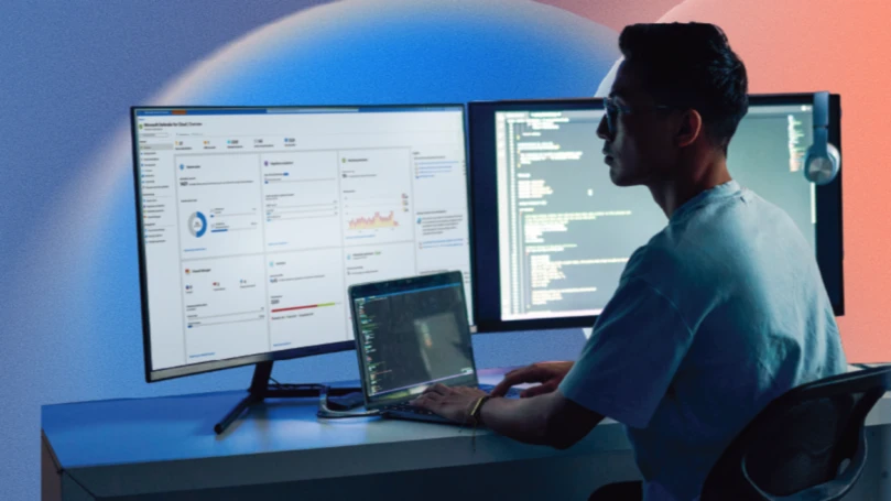 A man sitting at a desk with two computer screens