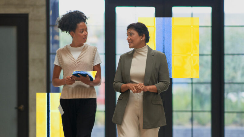 Two people walk through the lobby of an office building.