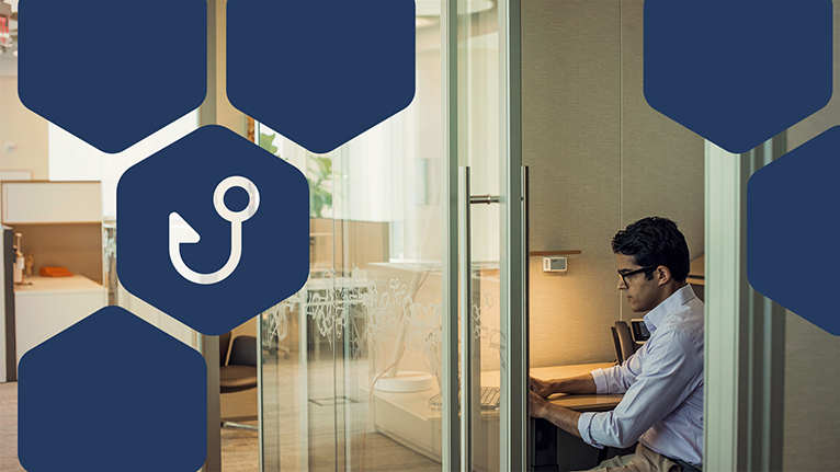 Photo of man in office using laptop, with blue hexagon overlays and the icon for phishing