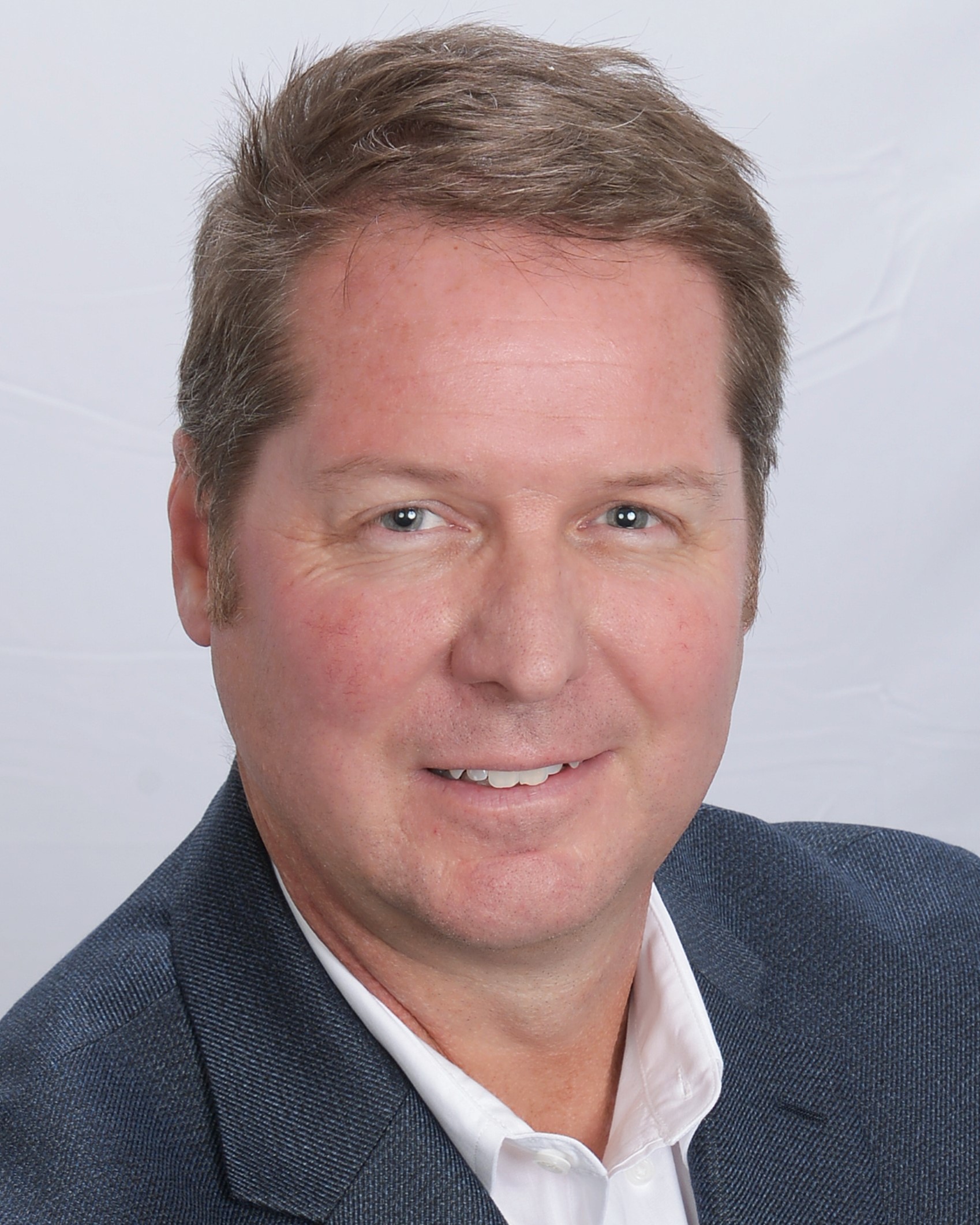 a man wearing a suit and tie smiling at the camera