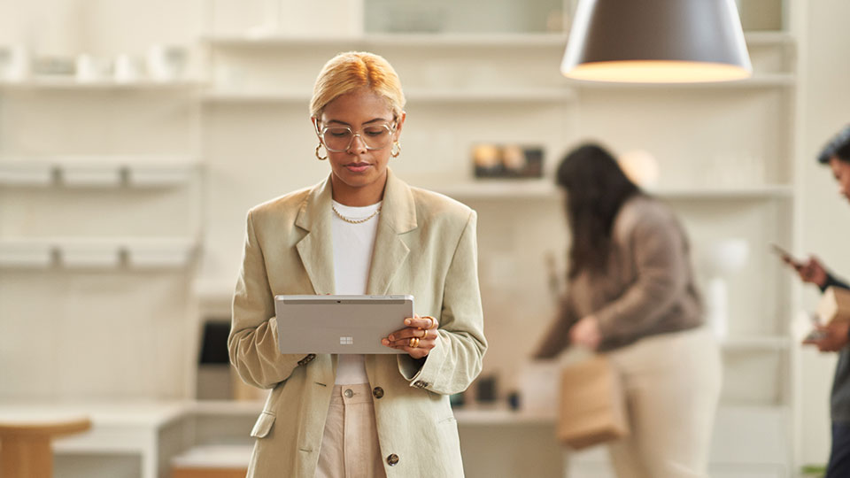 A woman stands consulting a tablet in an office environment