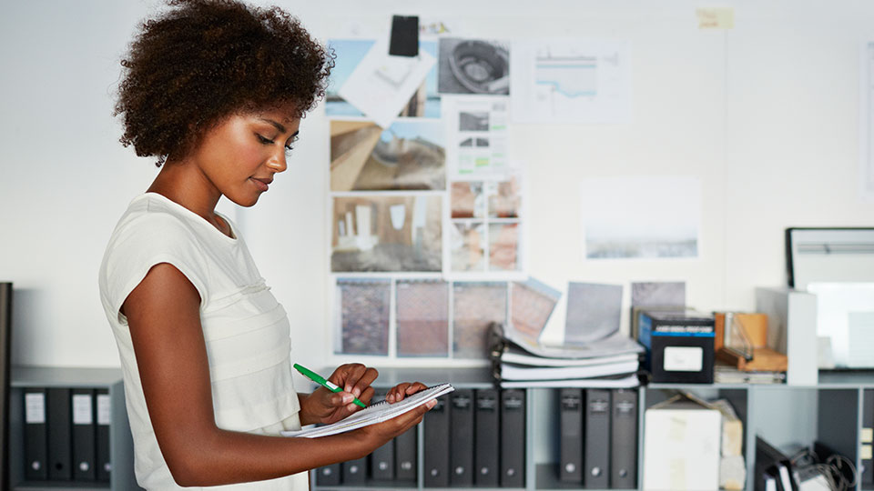 A woman writing in a notebook in an office environment