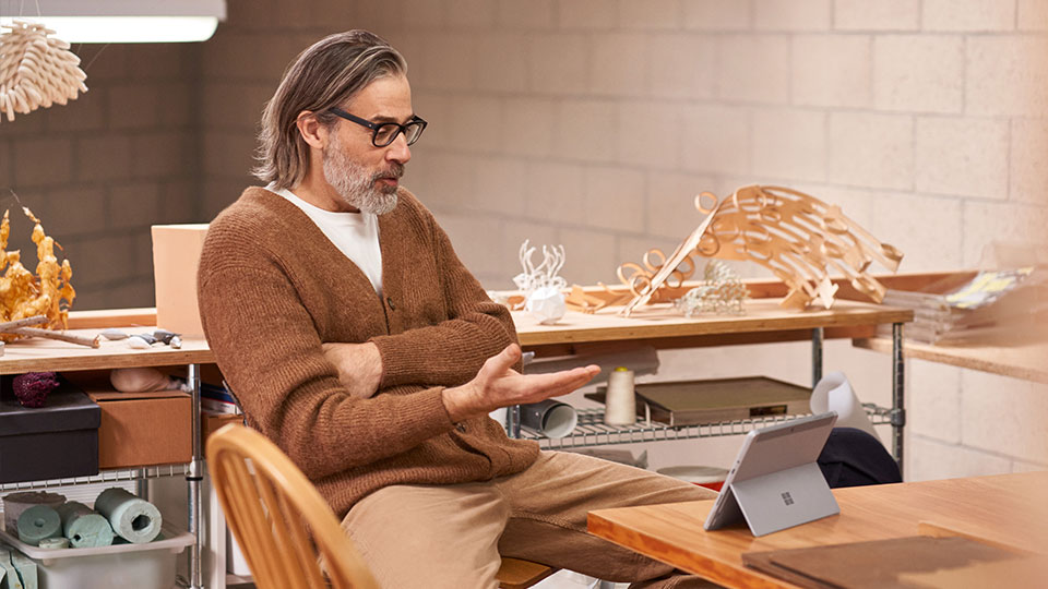 A man in a creative office engages in a video call on a tablet