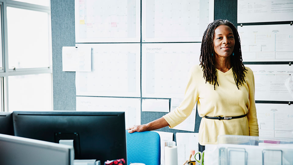 A woman stands near a computer workstation