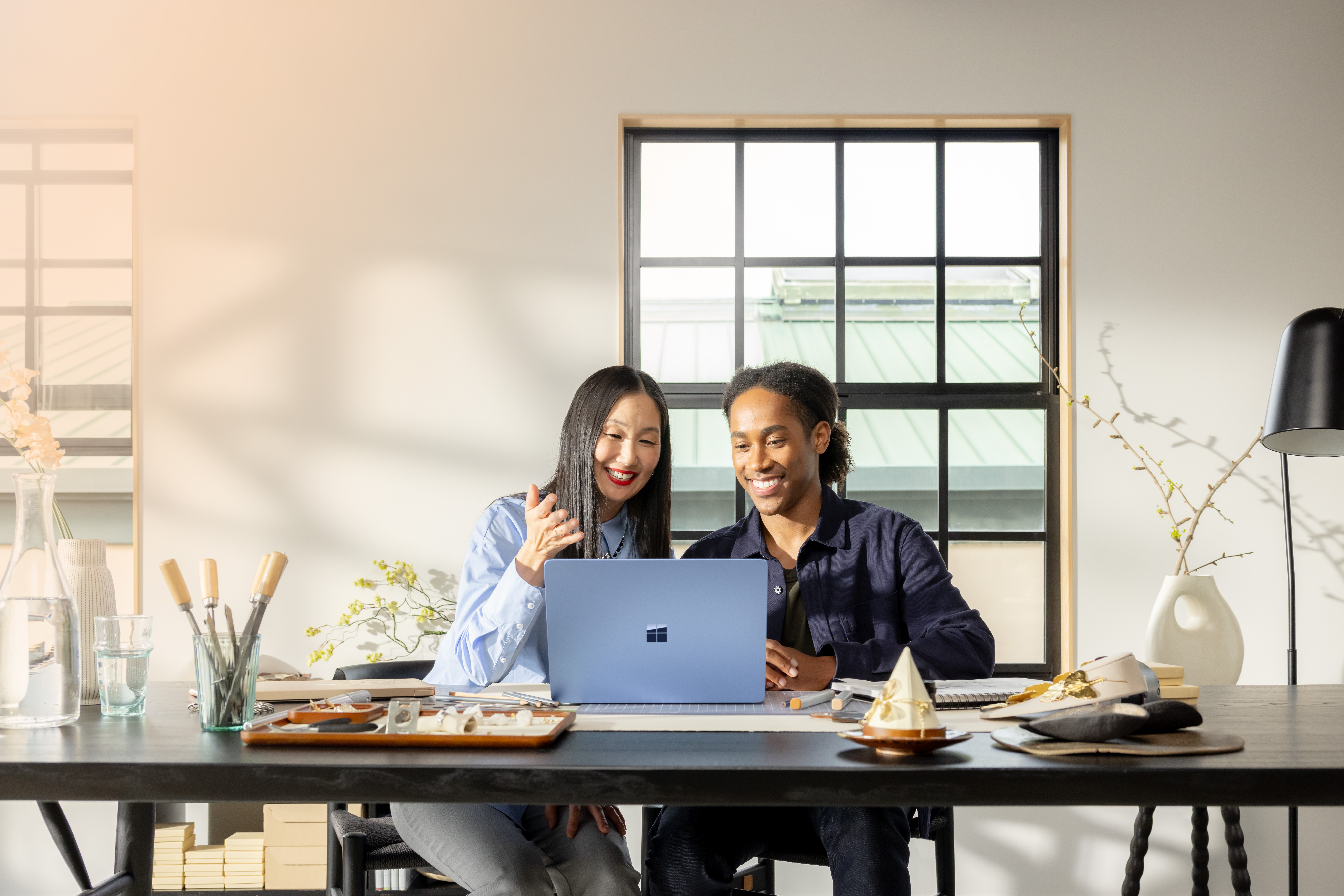Two people smiling at a table with a laptop computer.
