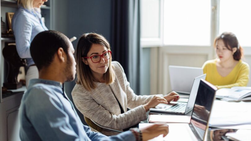A man and woman collaborating on a laptop in an office
