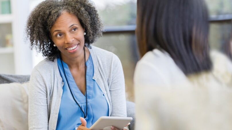 Female doctor talking with patient holding tablet.